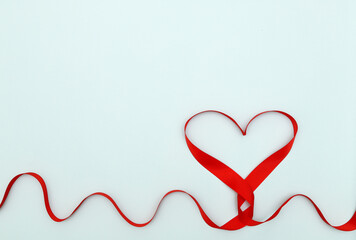 Heart made of red ribbon on a blue background. Concept: Creative Valentine's Day. the rhythm of the cardiogram.copy space
