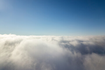 Aerial view from above of white puffy clouds in bright sunny day.