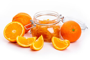 Orange jam in a glass jar and oranges on a white background