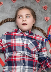 Portrait of cute dreamy beautiful girl lying on carpet with sweet heart cookies