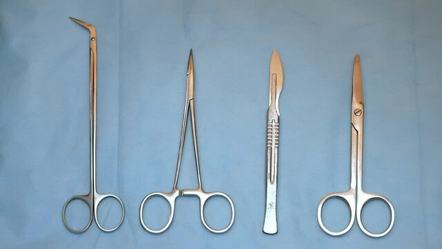 multiple surgery instruments on blue table above view. surgeon take surgical tools from table.
