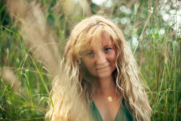 Portrait of a woman with light brown golden hair in green meadow.