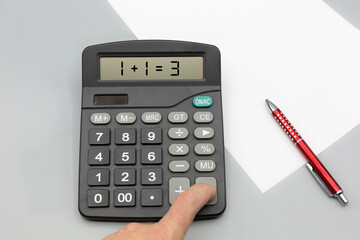 Calculator on office desk with incorrect calculation, paper and pen