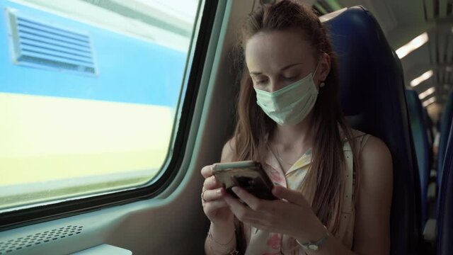 Tired woman in protective face mask travelling by train during coronavirus pandemic, female following rules and social distance in public places and transport. Young person in medical mask using