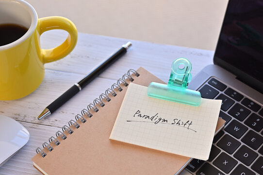 There's a note pinned to a clip on my desk. It says something like paradigm shift on it. There's a coffee and a pen and a laptop nearby.