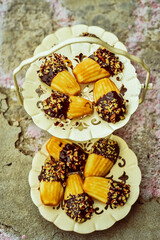 fancy three tier dessert plate filled with madeleine cookies dipped in chocolate and chopped nuts