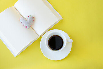 Obraz na płótnie Canvas 黄色の背景のコーヒーと見開きの本とハート