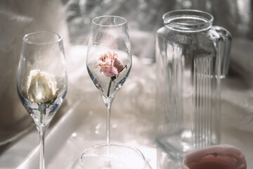 The jar and two empty glasses with dry roses on the table