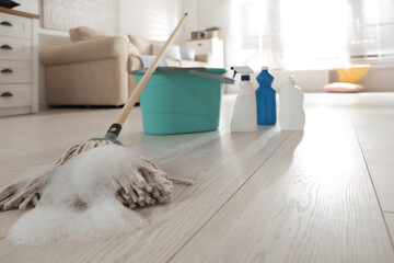 Bucket and different cleaning products indoors, focus on mop with foam © New Africa