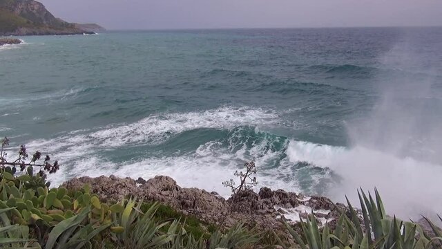 Rough sea with waves dashing on the rocks along the shoreline.