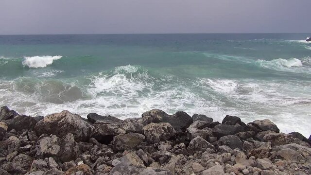 Rough sea with waves dashing on the rocks along the shoreline.