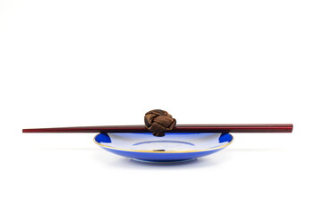 A set of chopsticks resting on top of an empty blue soy saucer/