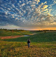 man on the banks of the picturesque river. tourist is enjoying the morning landscape. colorful spring sunrise