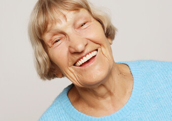 lifestyle,emotion and people concept: funny grandmother posing over grey background