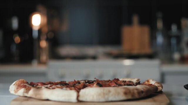 Chica le pone pimienta a una Pizza reci&eacute;n horneada en casa. 