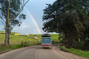 Truck on rural road in a country landscape with a rainbow in the background. Boyacá. Colombia.