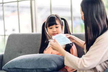 Portrait of enjoy happy love asian mother wearing protective mask for little asian girls child in quarantine for coronavirus with social distancing at home.covid19 concept