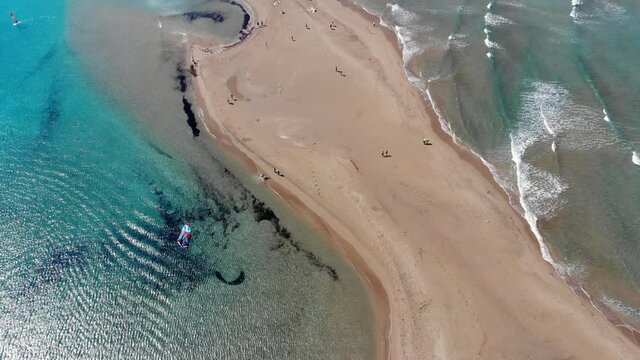 Scenic drone footage of Prasonisi peninsula in Rhodes in Greece surrounded by turquoise water. Kitesurfing. Aerial view on the waves on the Aegean Sea and calm flat water on the Mediterranean Sea.
