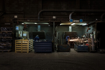Two men working welding with protective equipment in a factory.