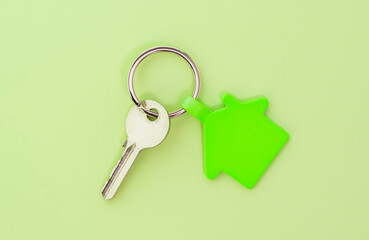 key chain with house symbol and keys on green background,Real estate concept