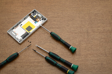 Phone panel and electronics repair tools on wooden table.