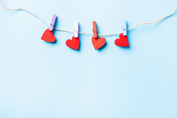 Valentine's day concept. red heart-shaped valentines decoration hanging with wood clips for happy love on the rope greeting card isolated on blue background with copy space