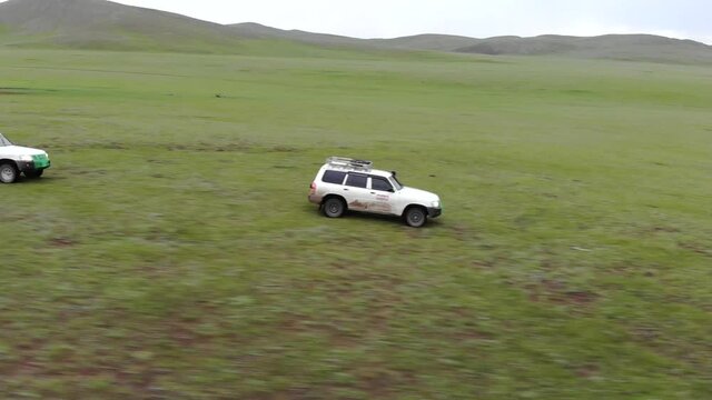 Two 4X4 suv cars driving in the treeless vast meadow. Crossing adventure hard way dirt road large big long nature natural vehicle car white nissan patrol terrain safari tour visit tourism go going 4K