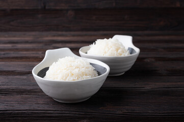 Bowl of boiled rice served on wooden table,