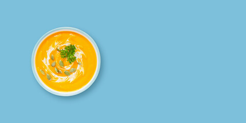 Pumpkin cream soup on a blue background.  Top view. Copy space. Banner