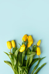 Yellow tulip flowers bouquet on blue background. Flat lay, top view, copy space. Banner for seasonal holiday, springtime concept, International Woman day, 8 march, Happy Easter greeting card