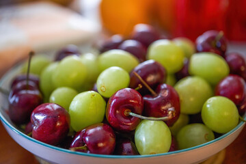 Naklejka na ściany i meble A dish of green grapes and cherries close-up