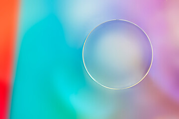 Oil droplet on water with colourful background and circle shape.