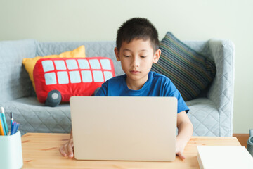 Asian boy learning online via internet with a tutor on laptop computer - 403732764