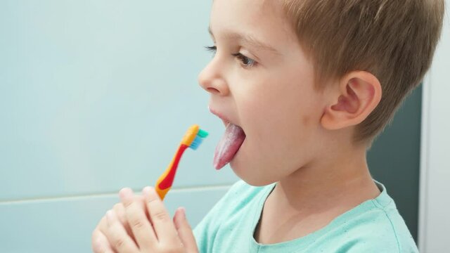 Portrait of little boy brushing teeth and cleaning tongue with toothbrush. CHild taking care of teeth and cleaning them