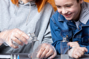 Chemistry education and study concept. Close-up of a boy and his mother, scientists pour water into a bottle with chemical elements, for experiments at home