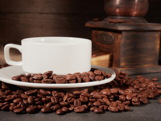 Antique vintage retro bronze coffee mill on black wooden board with roasted coffee beans