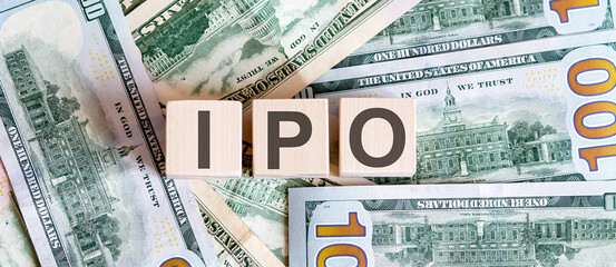 Concept words IPO Initial Public Offering on wooden blocks on a beautiful background from dollar bills.