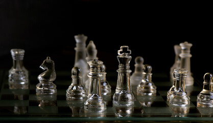 glass chess pieces are defending the king on board in dark