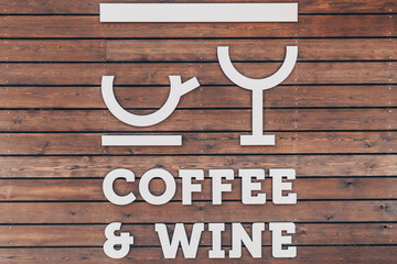 Stylized cup of coffee and a glass of wine on a wooden background. The words coffee and wine....