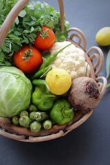Assorted organic vegetables in a heart shaped wooden basket. Fresh uncooked vegetable. cabbage, cauliflower, green garlic, fenugreek, okra, tomatoes, capsicum, beetroot, and lemon.