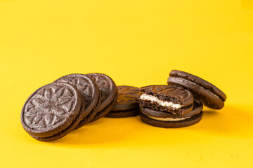 Chocolate sandwich cookies with vanilla cream filling on yellow background.