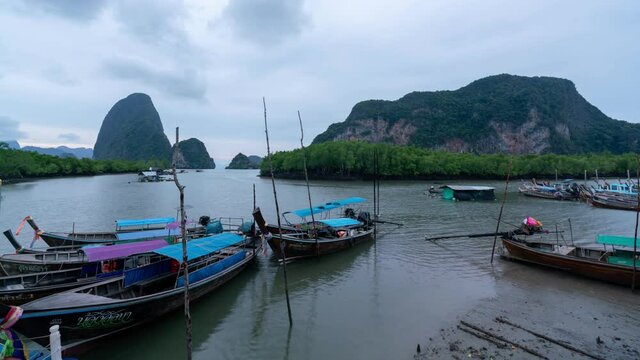 Timelapse Longtail fishing boats in the pier white storm clouds flowing fast over mountain rainforest, mangrove trees in the sea