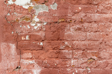 Full frame texture abstract of a shabby chic antique salmon red color painted brick wall background with an uneven artsy distressed appearance and deterioration