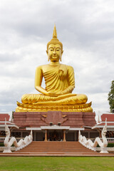 Fototapeta premium Beautiful Big Golden Buddha statue against blue sky in Thailand temple,khueang nai District, Ubon Ratchathani province, Thailand.Amazing Buddha image with sunny sky clouds.