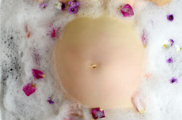 Pregnant woman and her belly in milk bath with flowers. Czech Republic. Europe.