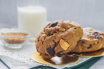 Close up high angle view chocolate chip cookies on a white table with a cup of milk in brown sugar background
