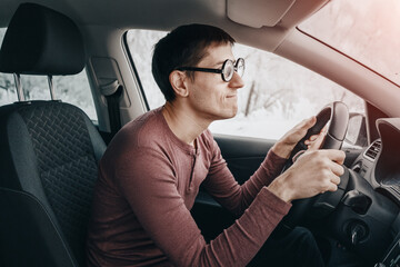 The ridiculous and idiotic nerd driver is staring at the road and holding the steering wheel. Concept of a novice driver and learning to drive in the city