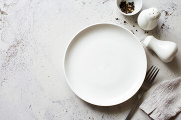 Food background- empty white plate, fork, napking,black peppers on gray stone slate