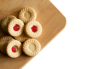 Strawberry jam cookies are placed on a wooden cutting board, isolated on white background.