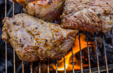 grilling pork steaks on flaming grill , shot with selective focus